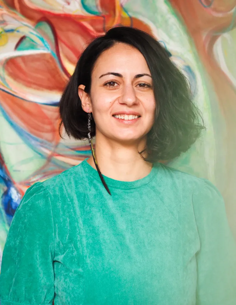 Adamantia Klonaris smiling in front of a colorful abstract painting.