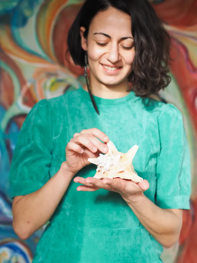 Adamantia holding a seashell by the water